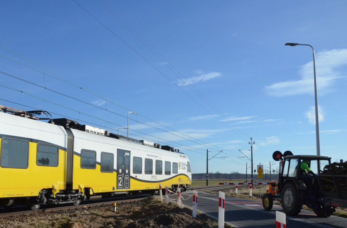 csm_Przejazd_kolejowo-_drogowy_na_drodze_powiatowej_w_Orzeszkowie._Rogatki_sa_zamkniete__pociag_Kolei_Dolnoslaskich_przejezdza_przez_przejazd._Przed_rogatkami_stoi_traktor._08c8867b07